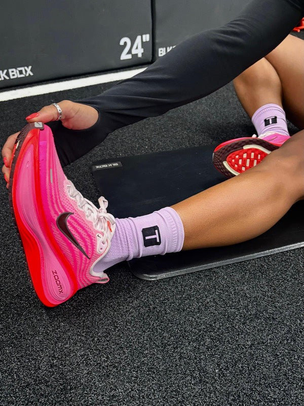 Athlete stretching on a mat in lilac TRED socks