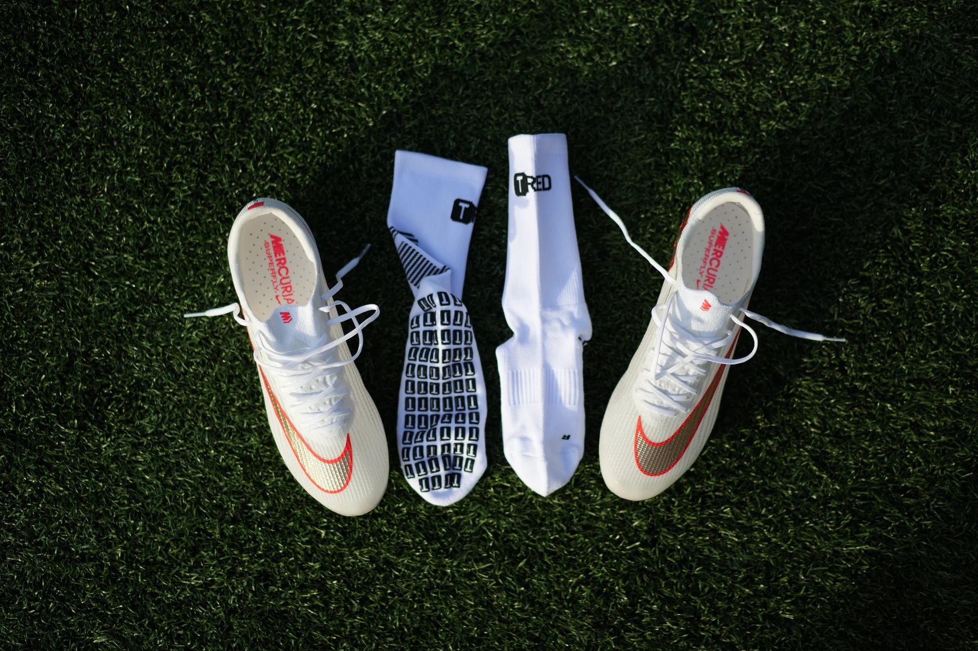 TRED 2.0 grip socks laid out between a pair of white boots, soles up